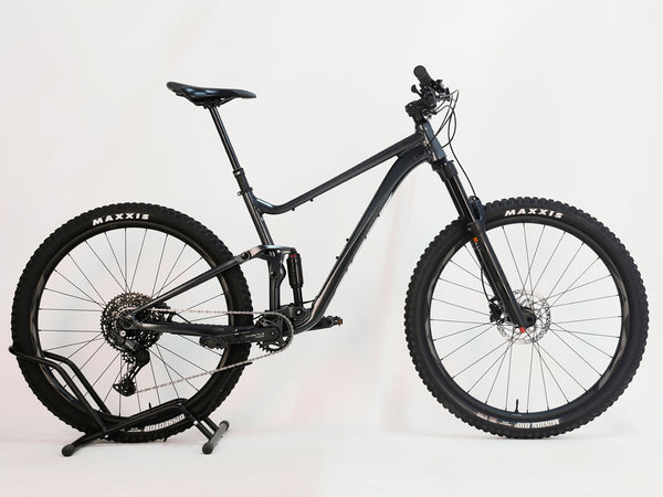 Close-up of the Giant Stance 29 2 2024/LARGE mountain bike showing the dropper post mechanism and saddle design.