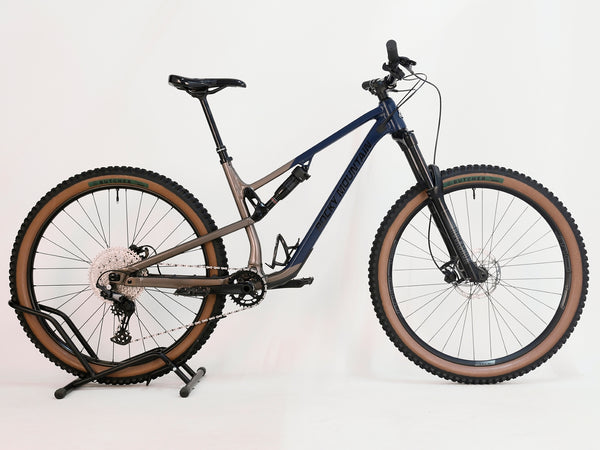 Front side angle of the Rocky Mountain Instinct Alloy 10 2023 mountain bike, showcasing its robust tyres and brake system, available at eMado Bikes.