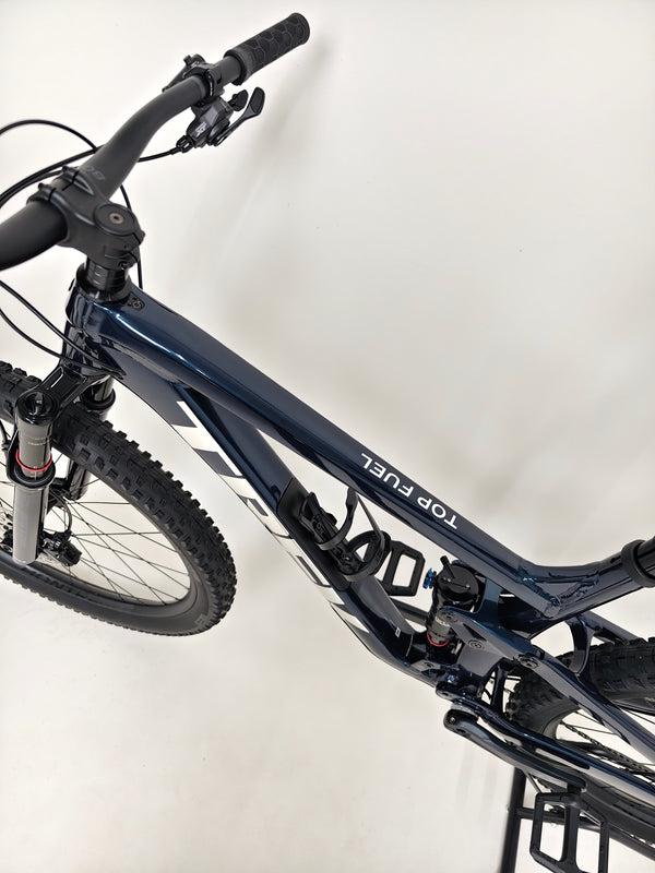 Trek Top Fuel 8 2024 Large Frame Full Suspension Bike at eMado - Photo showing the bike on display with sunlight reflections.