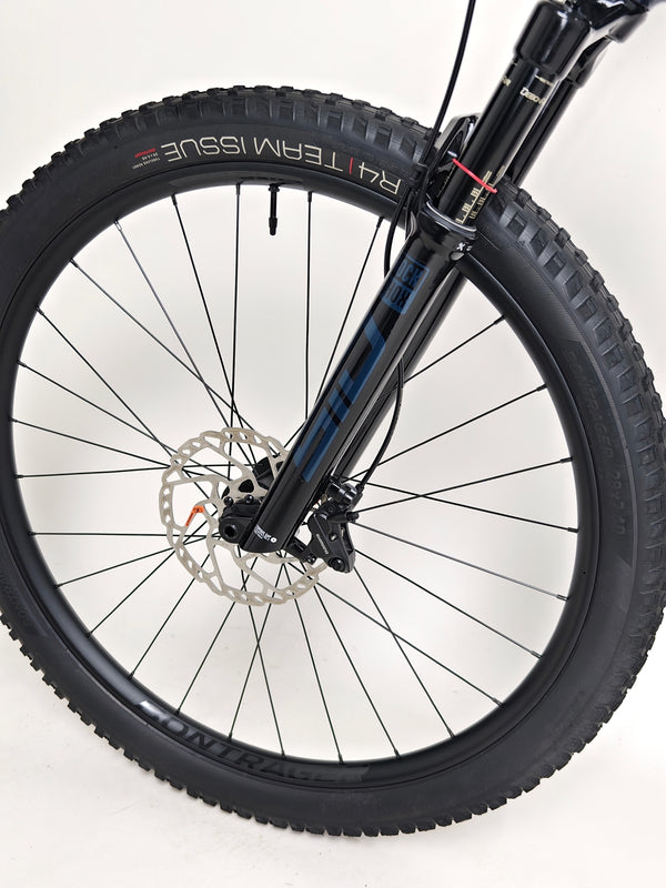 Trek Top Fuel 8 2024 Large Frame Full Suspension Bike at eMado - Scenic photo of the bike in action on a rough terrain.