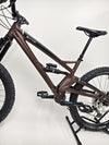 The Orange ALPINE 6 mountain bike parked against a backdrop of rugged cliffs.