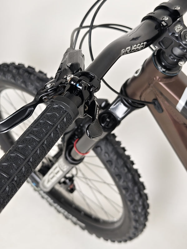 The Orange ALPINE 6 mountain bike resting in a picturesque field, ready for another ride.