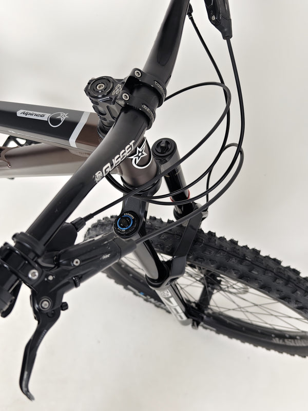 Close view of the gears and shifting mechanism on the Orange ALPINE 6 mountain bike.