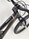 The Orange ALPINE 6 mountain bike on display at a cycling store, under bright lights.