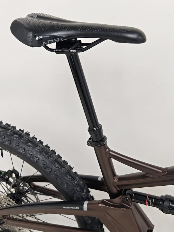 Detailed view of the Orange ALPINE 6's rear shock absorber functioning under pressure.