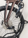 Eclectic view of the Orange ALPINE 6 mountain bike amidst nature, highlighting its adventurous spirit.