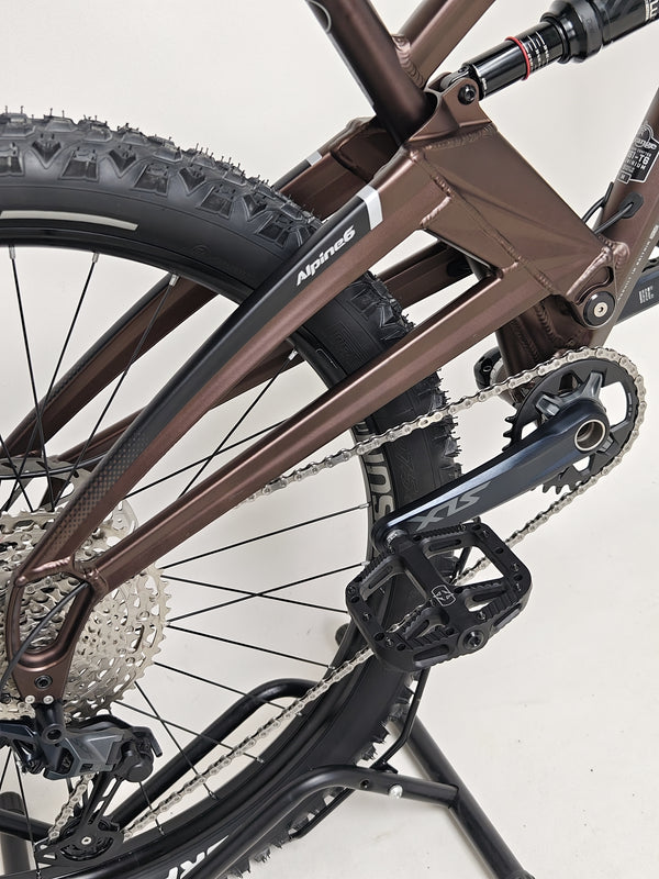A dynamic evening shot of the Orange ALPINE 6 mountain bike on a dirt trail.