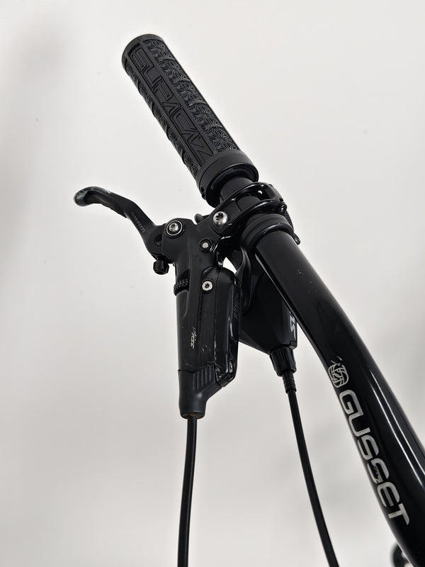 The Orange ALPINE 6 mountain bike parked at the start of a scenic race course.