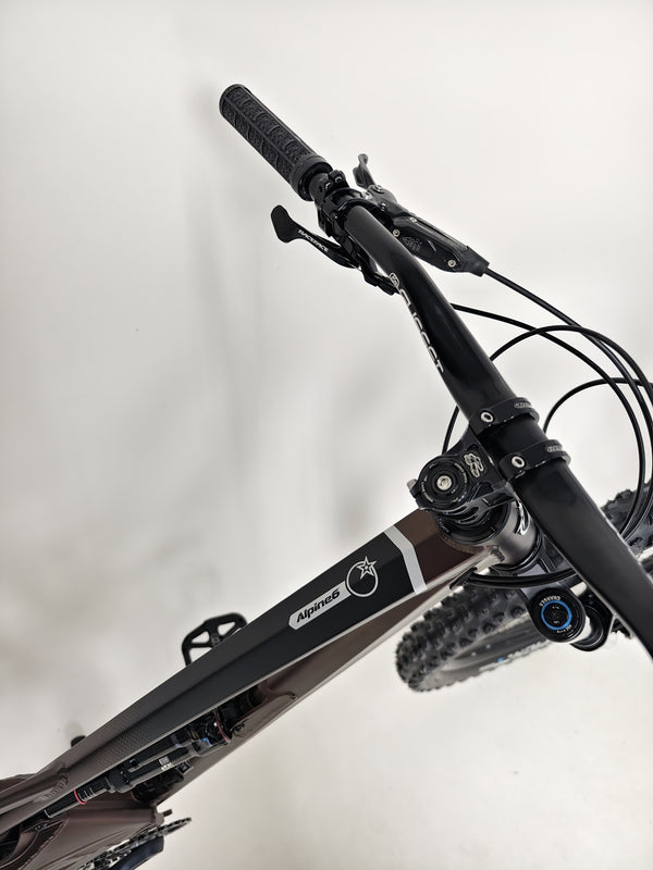 A close-up perspective of the Orange ALPINE 6 mountain bike's crankset and pedals.