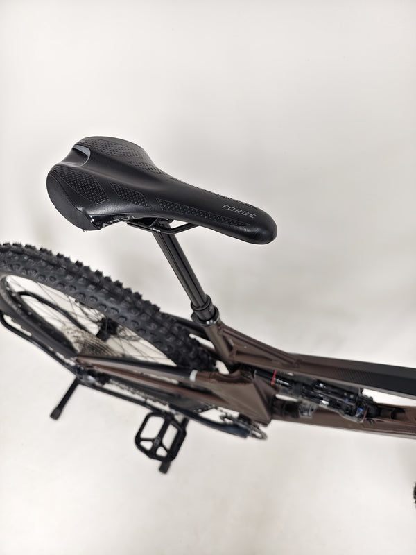 Profile view of the orange Orange ALPINE 6 mountain bike against a natural backdrop.