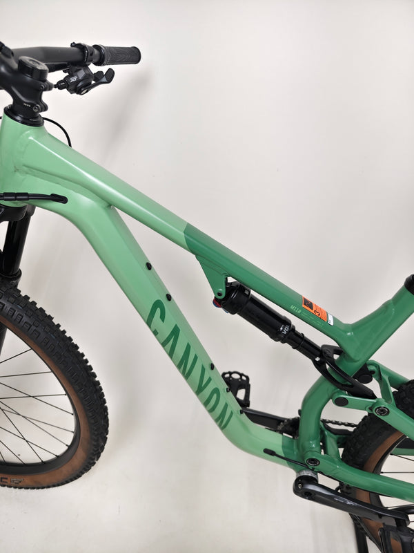 Action shot of the 2023 Canyon Neuron 7 Full Suspension Bike, Large size, riding on a trail, in Very Good Condition.